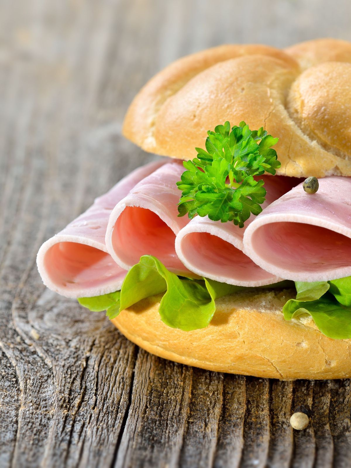 Garniertes Brötchen mit Schinkenwurst, Salatblatt und Petersilie - Roll with sliced ham sausage and lettuce leaf