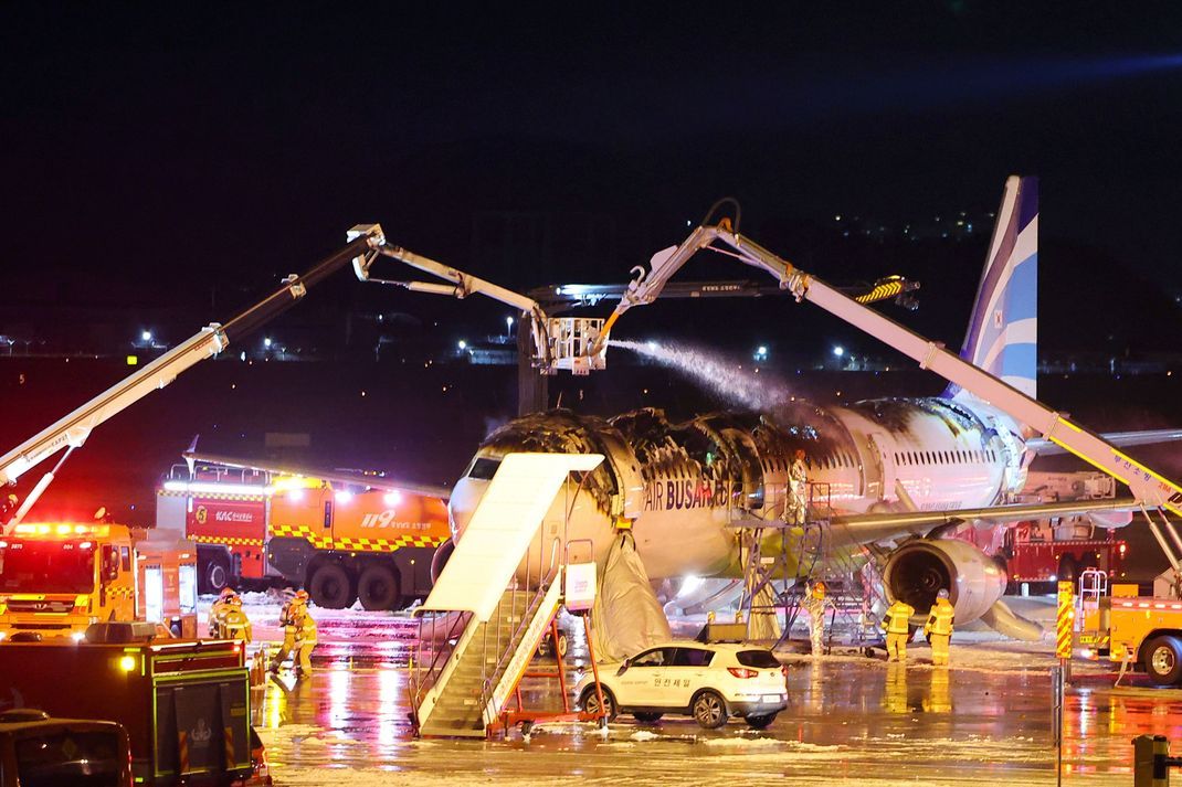 Feuerwehrleute arbeiten daran, das Feuer in einem Flugzeug der Air Busan am Gimhae International Airport zu löschen. 