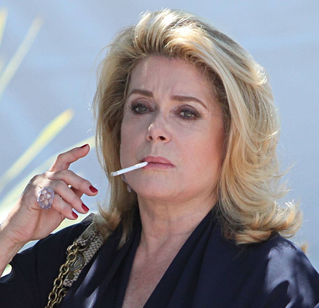 Catherine Deneuve genießt ihre Zigarette.