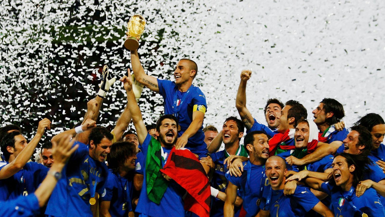 
                <strong>WM 2006 - Italien </strong><br>
                Kapitän Fabio Cannavaro reckt den WM-Pokal in die Höhe, während seine Teamkameraden frenetisch feiern. Beim Turnier in Deutschland gewinnt Italien im Elfmeterschießen gegen Frankreich zum vierten Mal die Weltmeisterschaft. Aufreger des Endspiels blieb der Kopfstoß und die folgende Rote Karte des zuvor überragenden französischen Spielmachers Zinedine Zidane.  
              