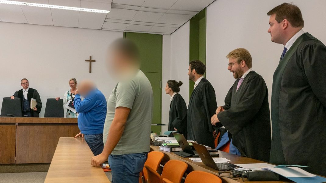 Richter Martin Hofmann (l.) sowie die beiden Angeklagten (vorne) zum Auftakt des Prozesses in München.