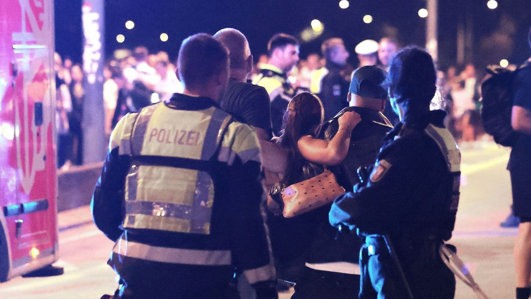 Ersthelfer und Polizisten tragen eine Verletze zu den Sanitätern auf einer Brücke.