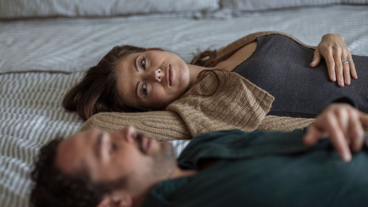 Woman looking at man while relaxing on bed at home