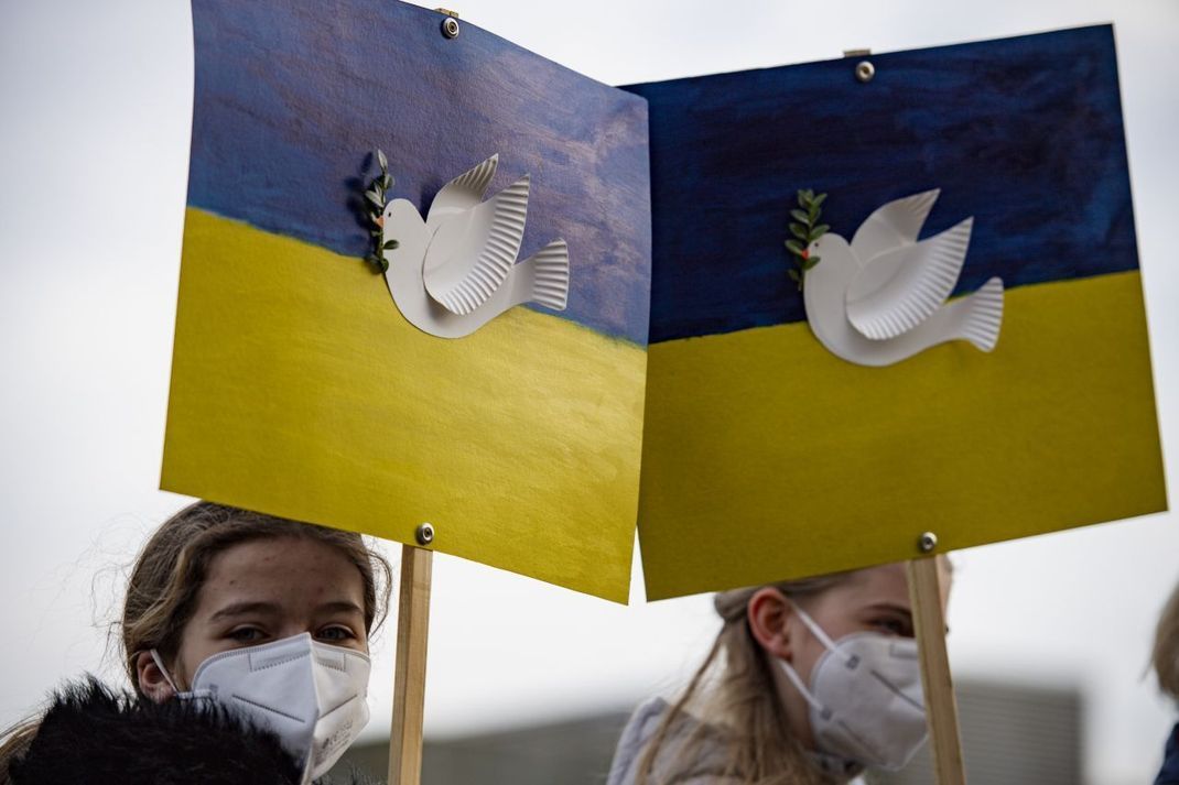Während einer Kundgebung für Frieden und Solidarität anlässlich des Krieges in der Ukraine halten zwei Mädchen in Remscheid (NRW) Schilder mit einer Friedenstaube und Olivenzweig.