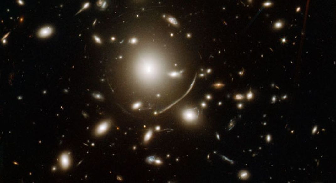 Ein riesiger Haufen aus Galaxien verbiegt das Licht dahinter liegender Galaxien, aufgenommen von Hubble.