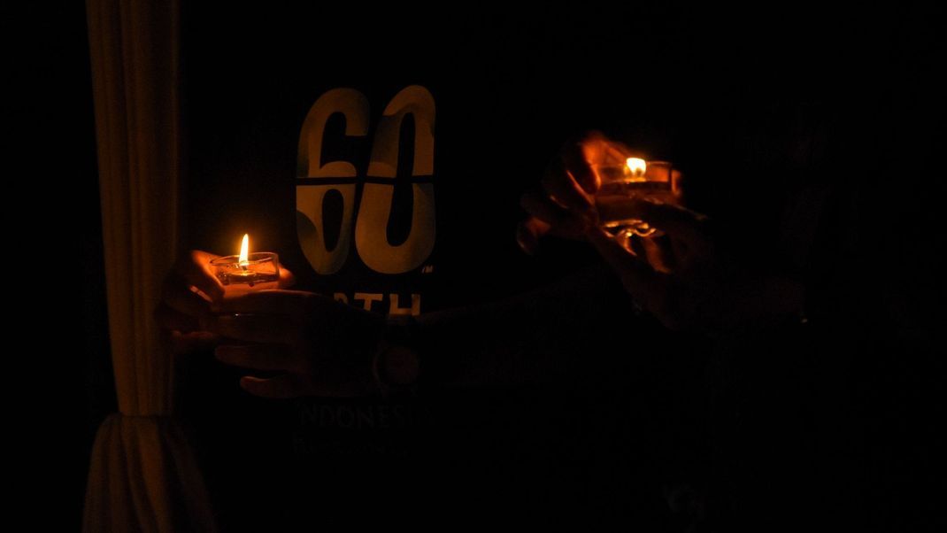 23. März 2024, Indonesien, Bandung: Menschen zünden Kerzen an, während sie im Rahmen der "Earth Hour" eine Stunde lang im Dunkeln sitzen.