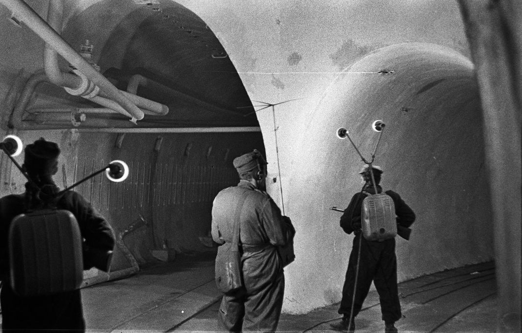 Ein historisches Foto mit polnischen Soldaten, die zu Beginn der 1950er-Jahre einen verlassenen Tunnel des Ostwalls erkunden.