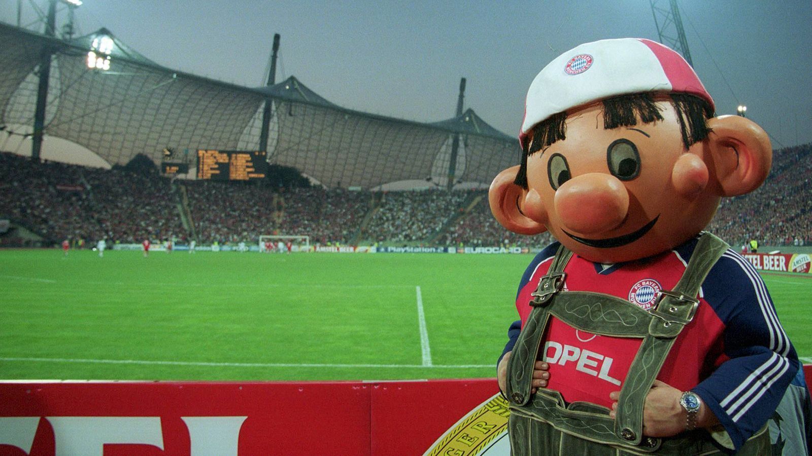 
                <strong>FC Bayern München: Die Maskottchen im Wandel der Zeit</strong><br>
                Bazi im alten Olympiastadion. Es scheint ihm gut zu gehen, auch wenn die Beulen im Gesicht eigentlich Anlass zur Sorge bereiten sollten.
              