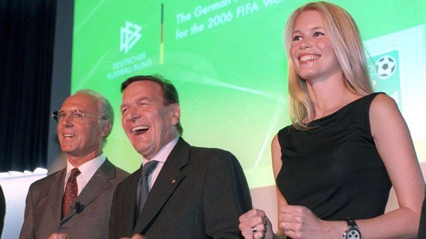 
                <strong>Franz Beckenbauer anno 2000</strong><br>
                2000 holte Beckenbauer als Vorsitzender des Bewerbungskomitees die WM 2006 nach Deutschland. Das Bild zeigt Beckenbauer mit den Delegationsmitgliedern Claudia Schiffer und Gerhard Schröder bei der Länderpräsentation.
              