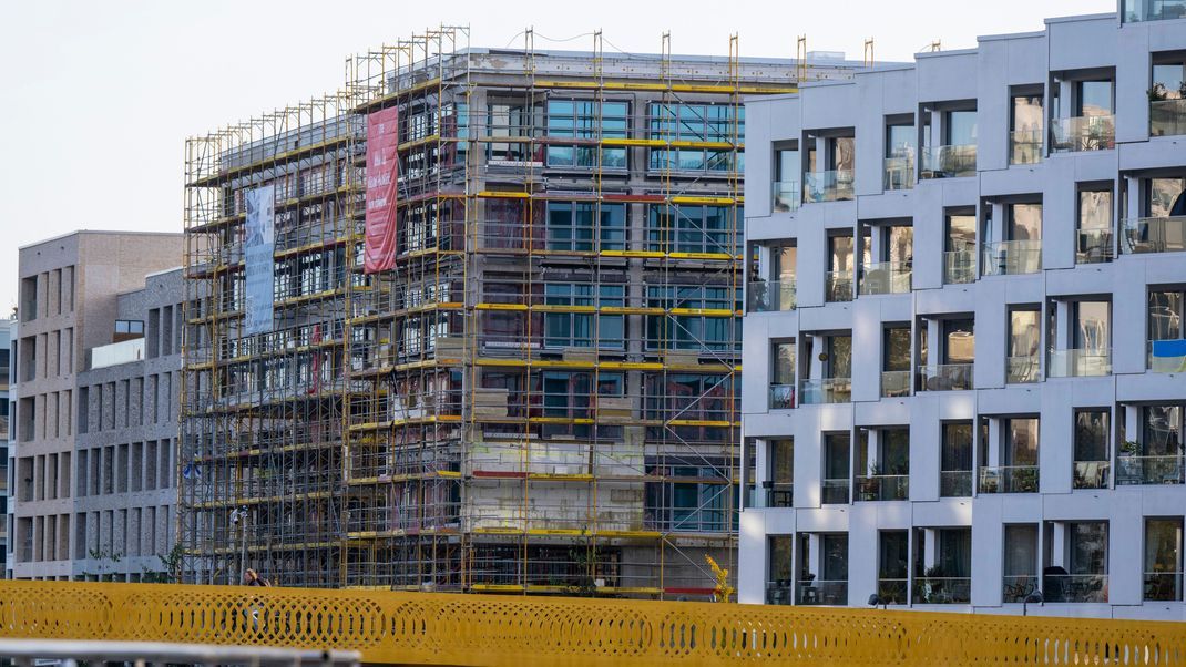 Ein Baugerüst steht an der Fassade von einem nicht fertig gebauten Wohnhaus auf einer Baustelle im Zentrum Berlins.