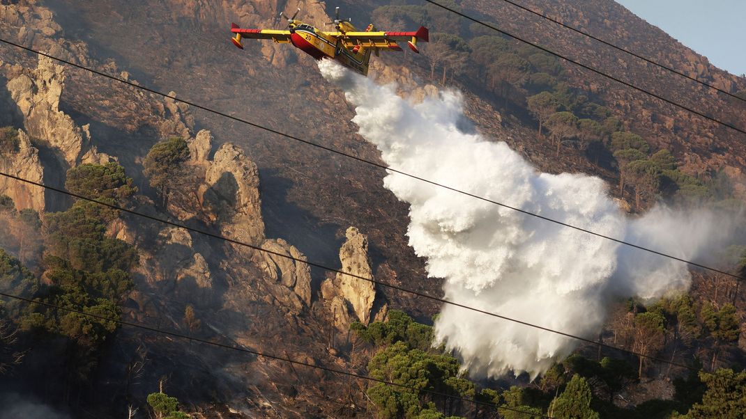 Ein Löschflugzeug wirft Wasser über einem Waldbrand auf einem Berg in Sizilien ab. (Symbolbild)