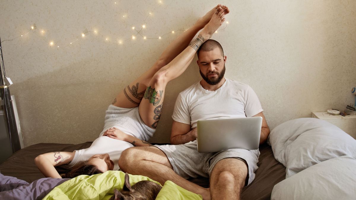 Man working with his laptop computer while his lovely woman relaxing nearby