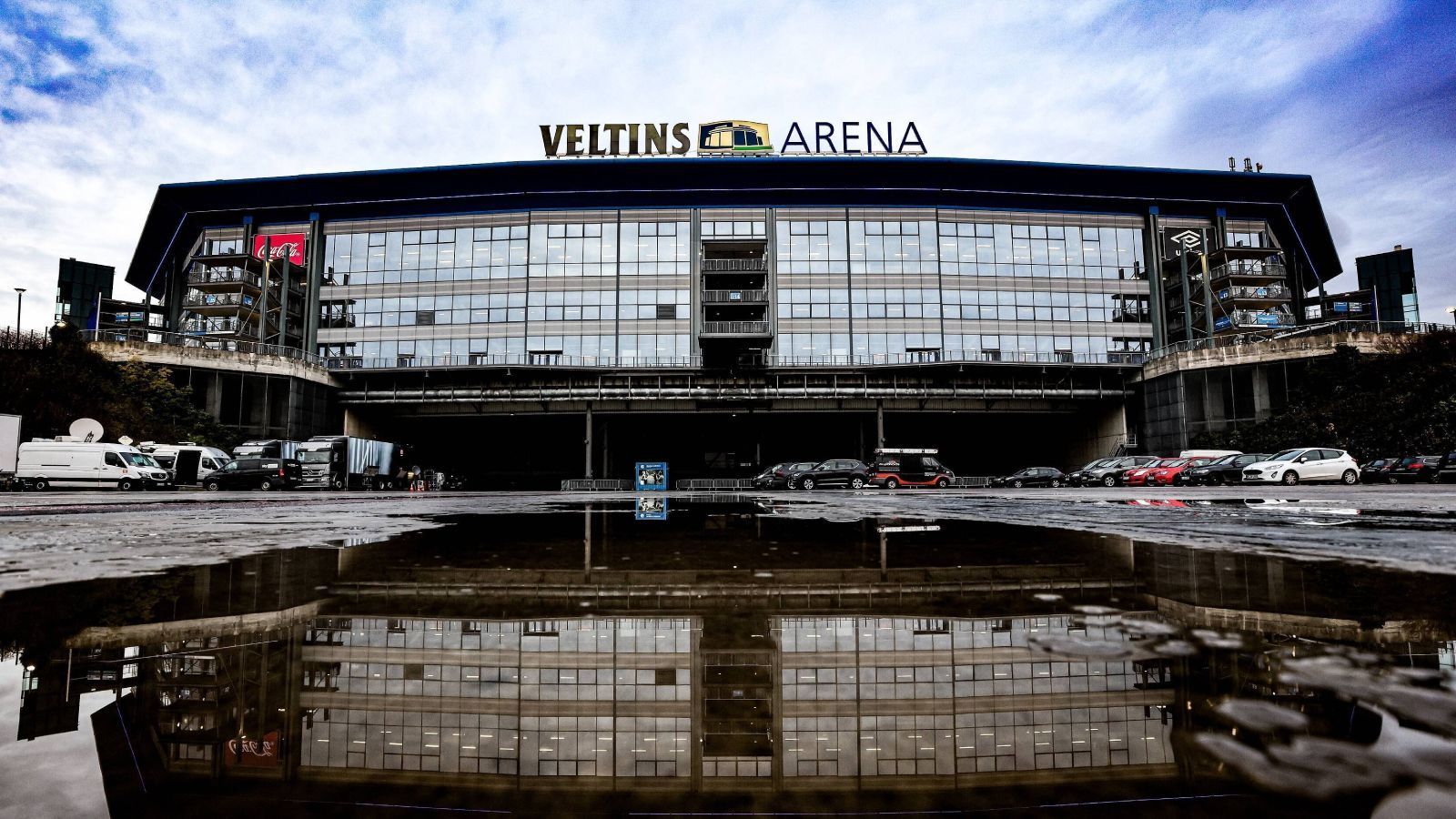 
                <strong>Platz 9: Veltins-Arena (FC Schalke 04)</strong><br>
                Die Veltins-Arena in Gelsenkirchen ist mehr als nur ein Fußballstadion, es ist ein gesamter Komplex, der über der Stadt thront. Die Heimat des FC Schalke 04 ist trotz ihrer mittlerweile 20 Jahre immer noch ein hochmodernes Stadion. Im Stadionumlauf gibt es vom alten, mittlerweile modernisierten, Parkstadion bis hin zu einer Wall of Fame viel zu entdecken. Auch mit dem Auto ist die Anreise laut vielen Erfahrungsberichten leicht, da rund um die ganze Arena eine Menge Parkplätze verteilt sind. Allerdings sind die Wege so weit, dass ein Shuttle Service oder kostenlose Stadtkarten von Gelsenkirchen keine schlechten Ideen wären. Dann lieber mit der Straßenbahn die Schalker Meile runter - herrlich! 
              