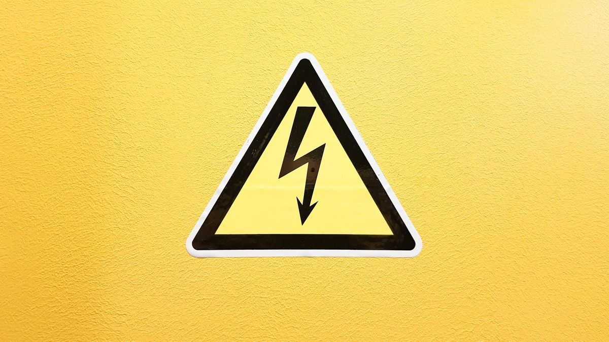 Warnschild Hochspannung auf einer gelben Wand