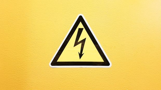 Warnschild Hochspannung auf einer gelben Wand