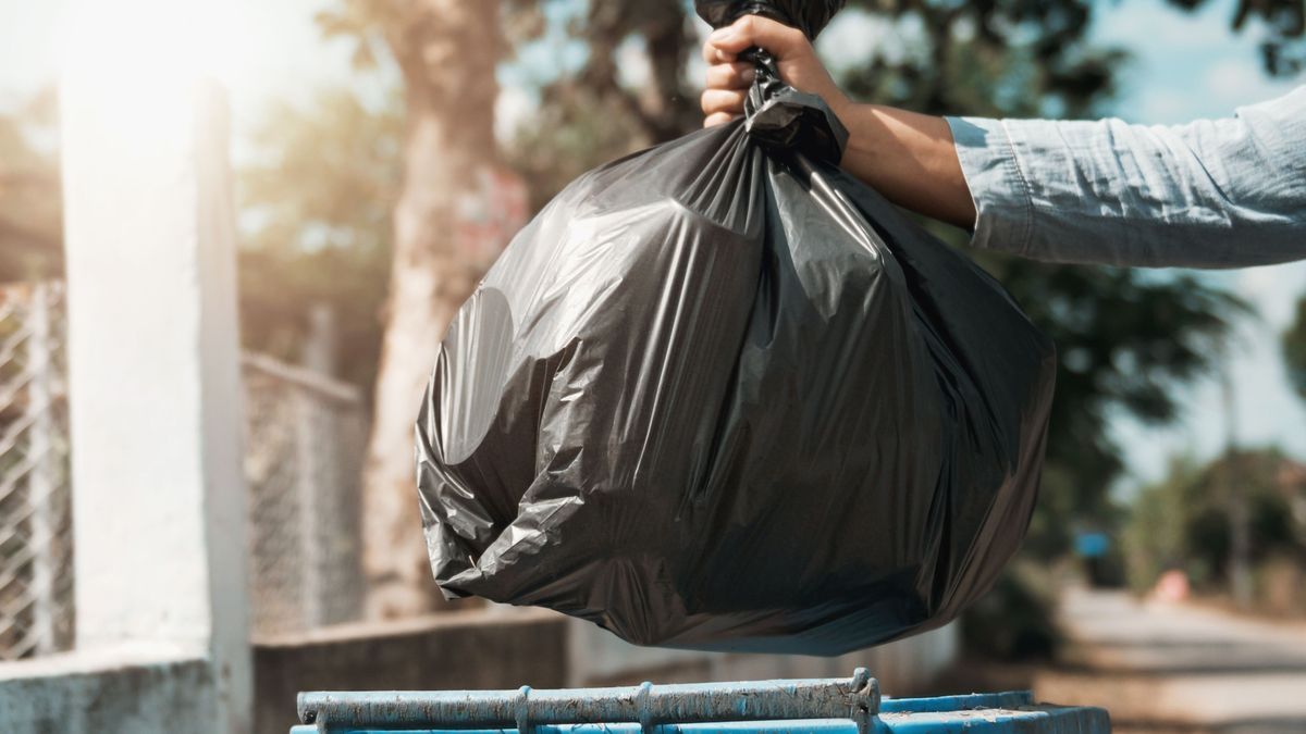 woman hand holding garbage black bag put in to trash