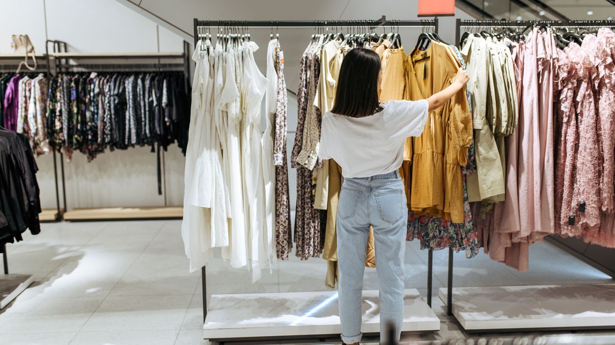 Woman choosing elegant dress in clothing store