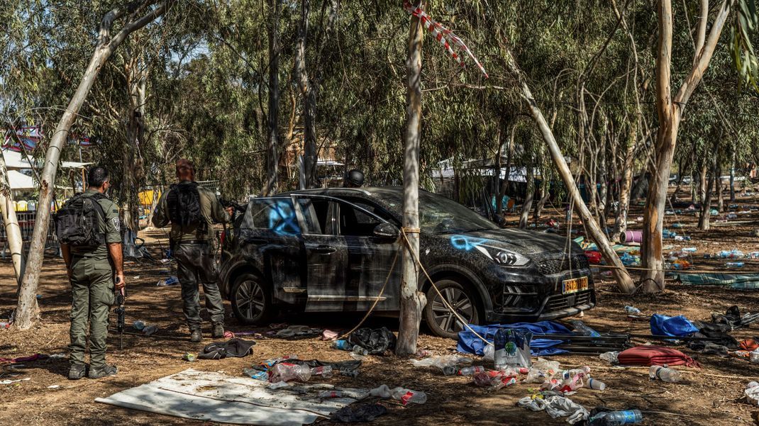 Israelische Soldaten stehen neben einem verlassenen Auto auf dem Gelände des Supernova-Wüstenmusikfestivals, nachdem es den israelischen Streitkräften gelungen ist, die Gegend um Re'im zu sichern. 
