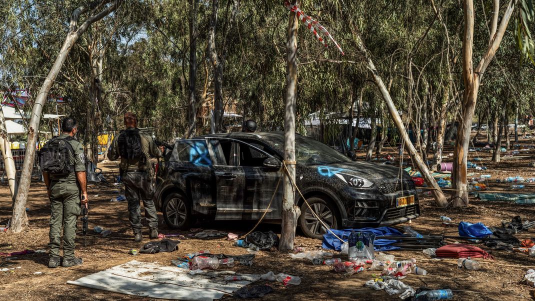 Israelische Soldaten stehen neben einem verlassenen Auto auf dem Gelände des Supernova-Wüstenmusikfestivals, nachdem es den israelischen Streitkräften gelungen ist, die Gegend um Re'im zu sichern. 