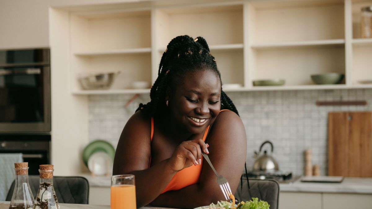 Beautiful curvy African woman enjoying healthy eating for lunch at home