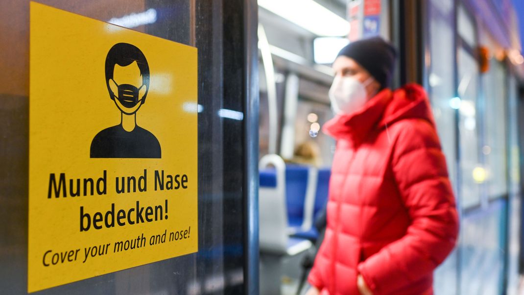 Eine Frau steigt mit FFP2-Maske in eine Trambahn ein.