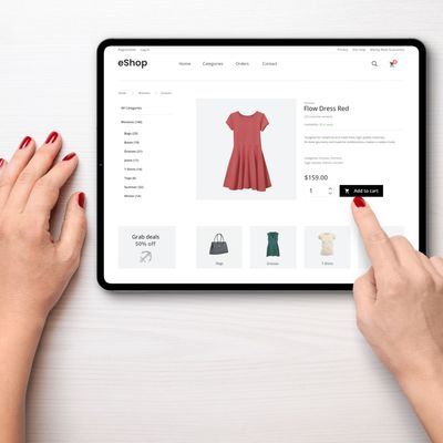 Online shopping with a tablet. Red women's dress on the e-commerce web page