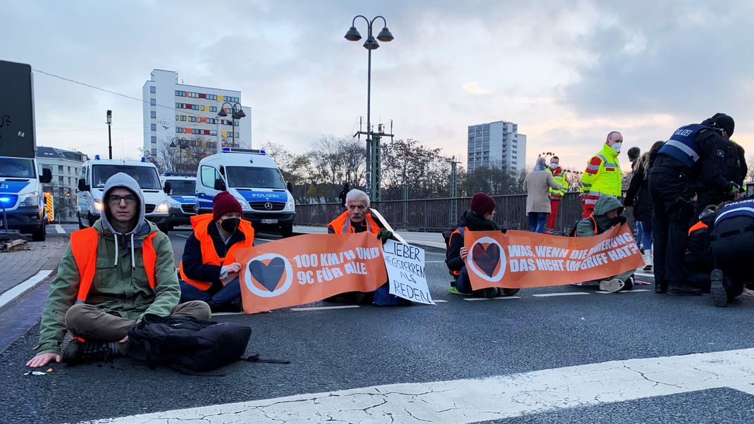 Aktivisten der Gruppe "Letzte Generation" haben sich am 9. Dezember auf einer mehrspurigen Straße am Hauptbahnhof in Mainz mit einer Hand auf dem Asphalt festgeklebt. 