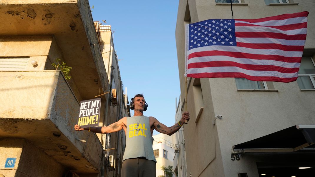 Ein Mann schwenkt die US-Flagge, während Israelis in der Nähe des Hotels protestieren, in dem US-Außenminister Blinken während seines Besuchs beim israelischen Ministerpräsidenten Netanjahu und der Führung über ein Abkommen zur Beendigung des Krieges im Gazastreifen und zur Befreiung der von der Hamas am 7. Oktober gefangen genommenen Geiseln untergebracht ist.&nbsp;