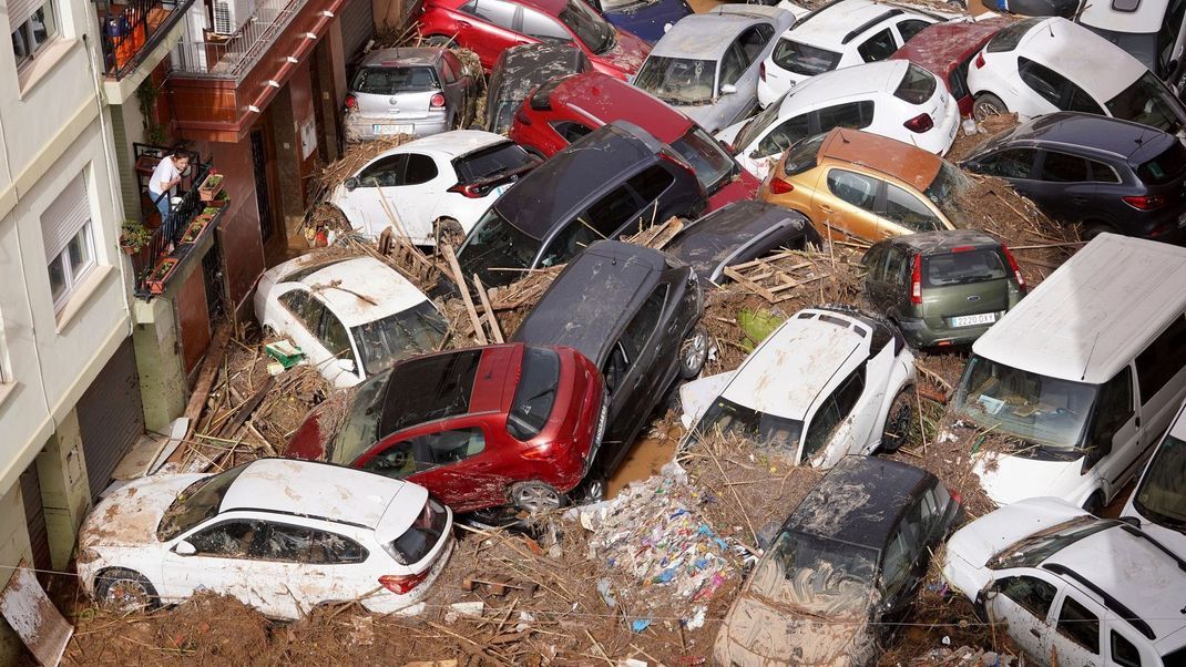 30. Oktober 2024, Spanien, Valencia: Anwohner:innen betrachten durch die Wassermassen aufgestapelte Autos.