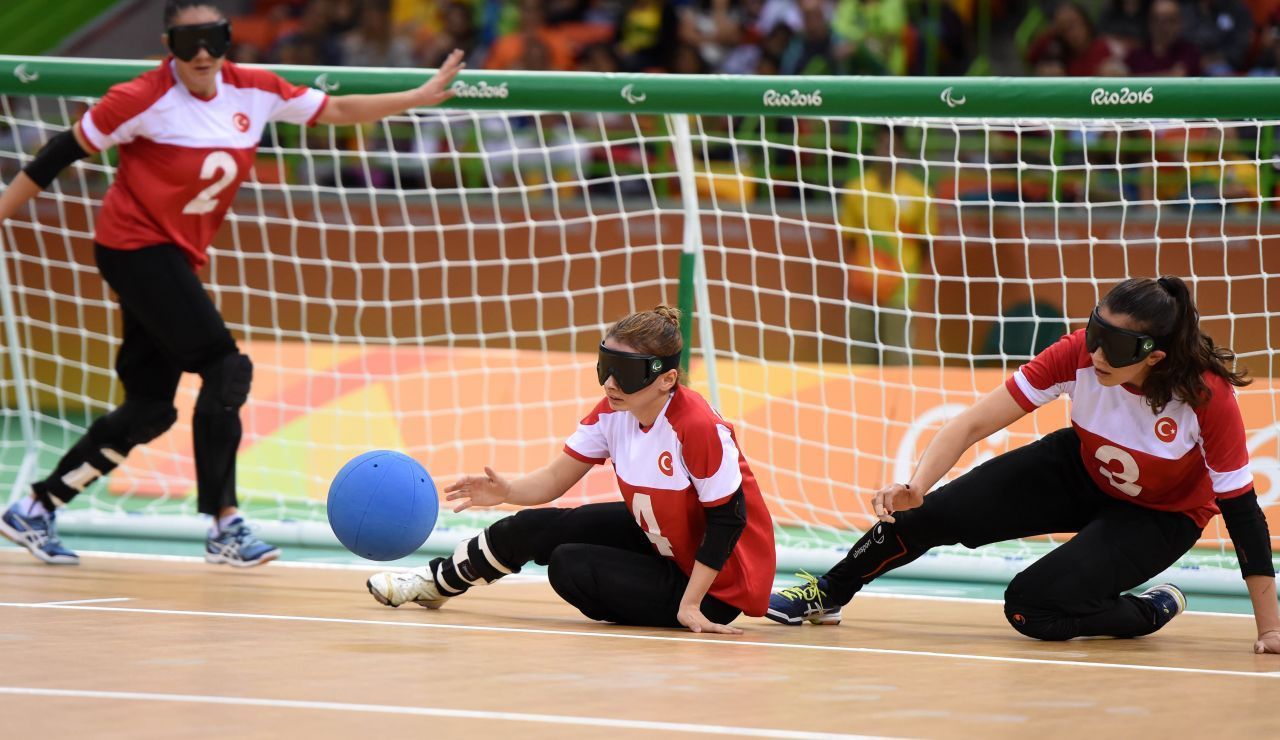 Goalball: 2 sehbehinderte Dreierteams spielen gegeneinander. Ziel ist es, einen Klingelball ins gegnerische Tor zu bugsieren, das sich über die gesamten 9 Meter Breite am Ende des Spielfeldes erstreckt. Die eigenen Spieler:innen verteidigen es nicht nur, sondern setzen auch zum Gegenangriff an. Das Spiel ist sehr temporeich und dauert 2-mal 12 Minuten. Das Foto zeigt das türkische Frauen-Team in Rio 2016.