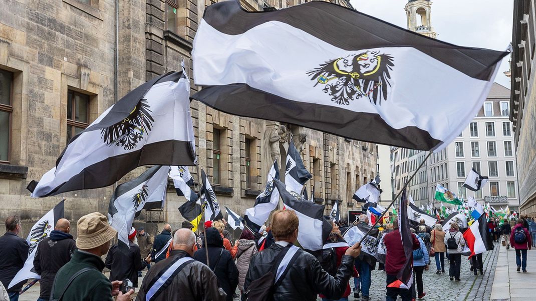 Mehrere hundert Teilnehmer einer Demonstration ziehen mit Flaggen vom Königreich Preußen (schwarz-weiß-schwarz mit Adler) durch die Dresdner Innenstadt. 