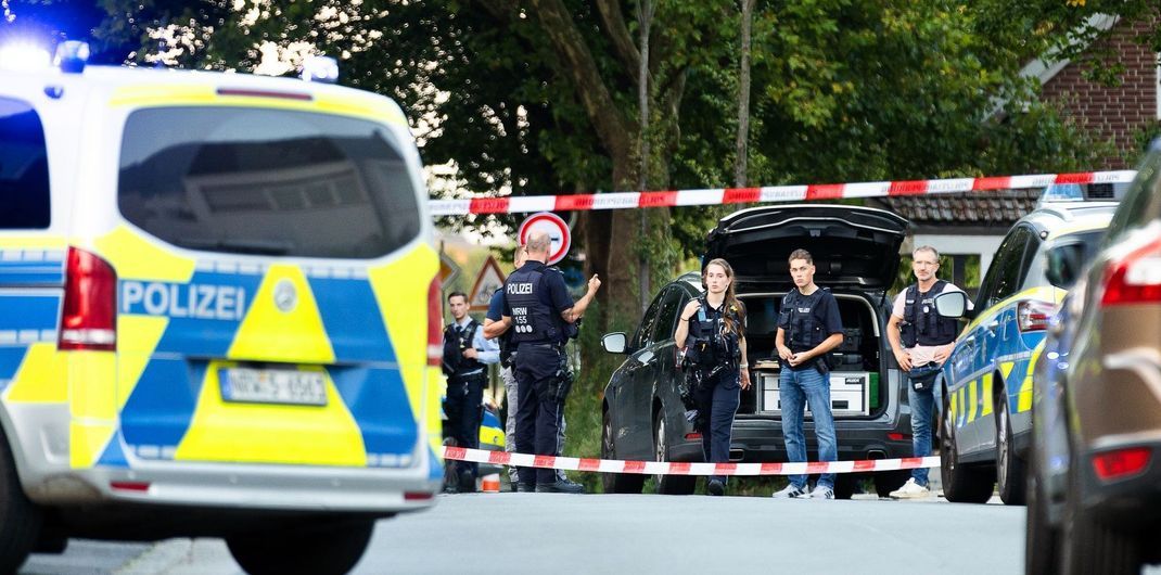 Einsatzkräfte der Polizei stehen an einem Tatort zwischen Fahrzeugen. Bei einem Schusswaffeneinsatz der Polizei ist ein mutmaßlicher Messerangreifer tödlich getroffen worden.