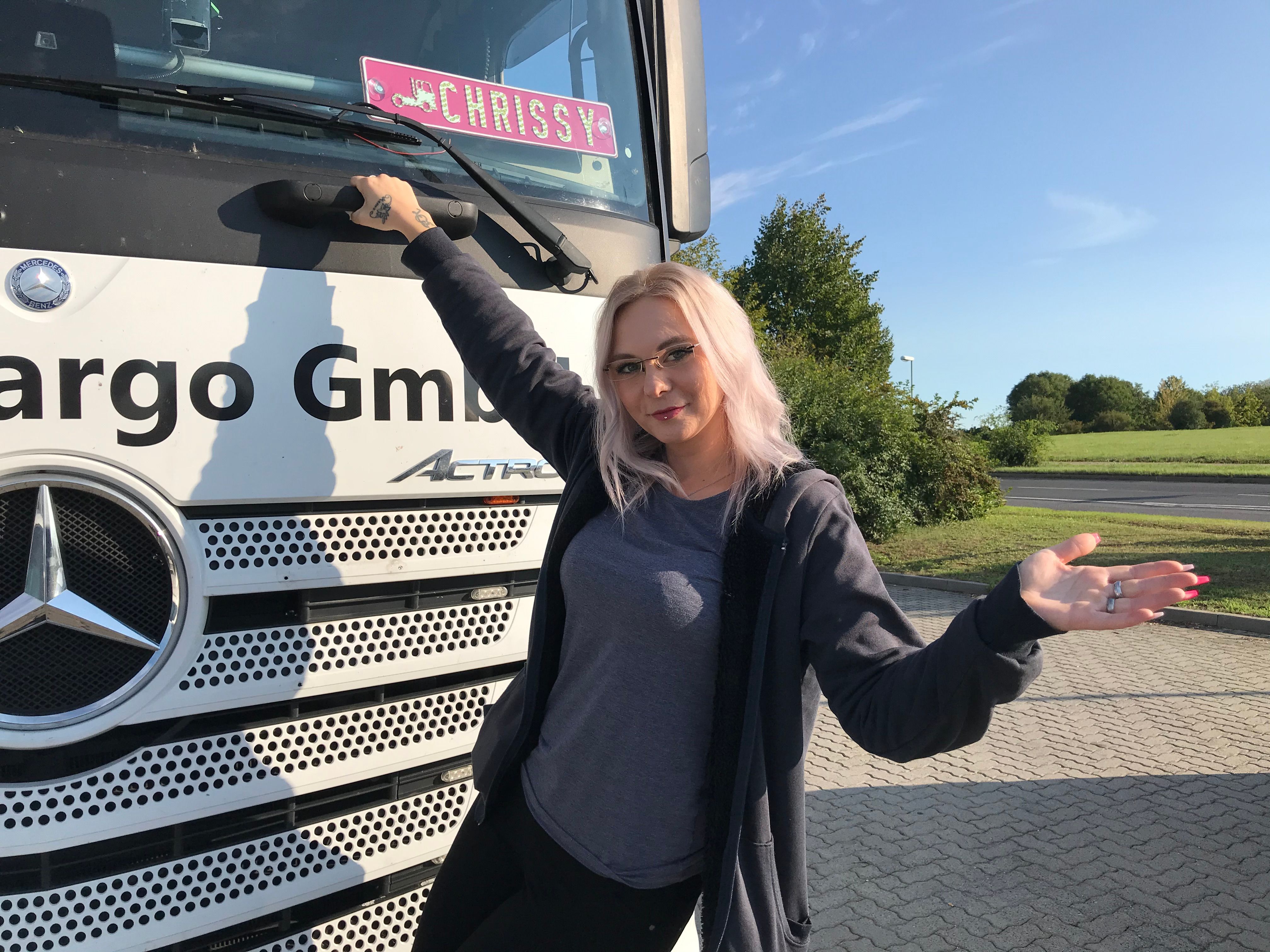 Vor einem weißen LKW zeigt sich "Trucker Babe" Chrissy.