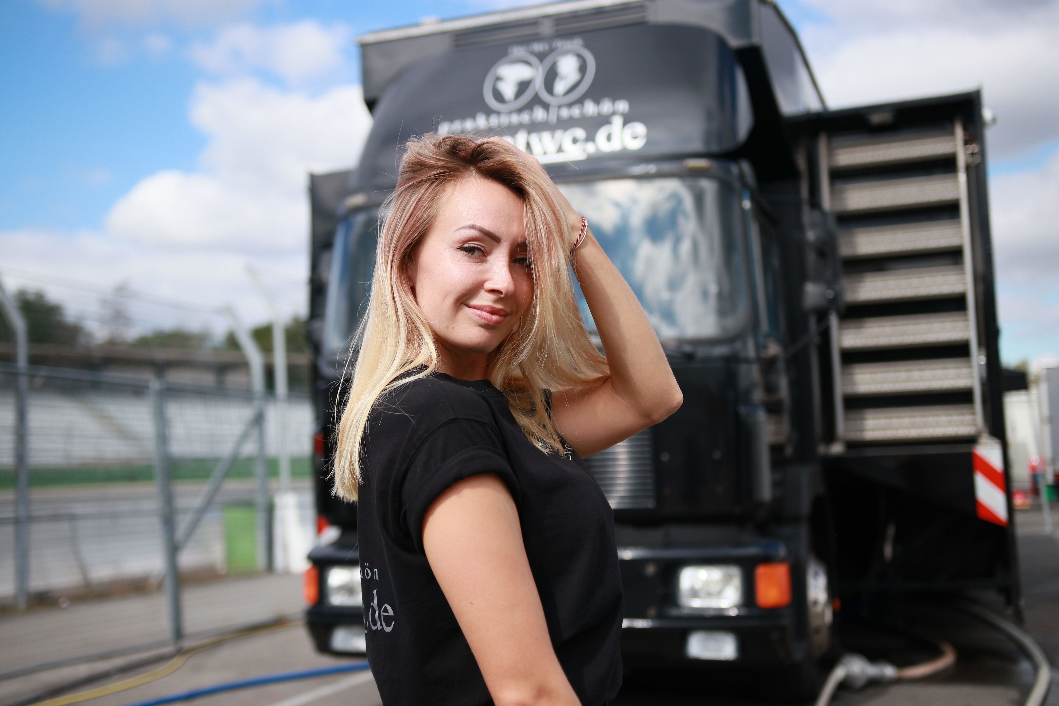 "Trucker Babe" Julia steht seitlich vor ihrem Truck und lächelt in die Kamera. 