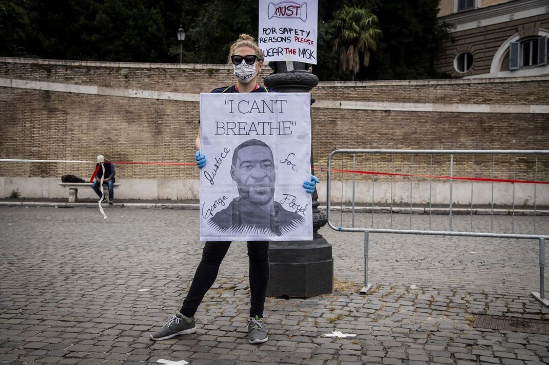 Eine Demonstrantin mit Plakat. Darauf zu sehen: George Floyd, der von einem Polizisten getötet wurde.