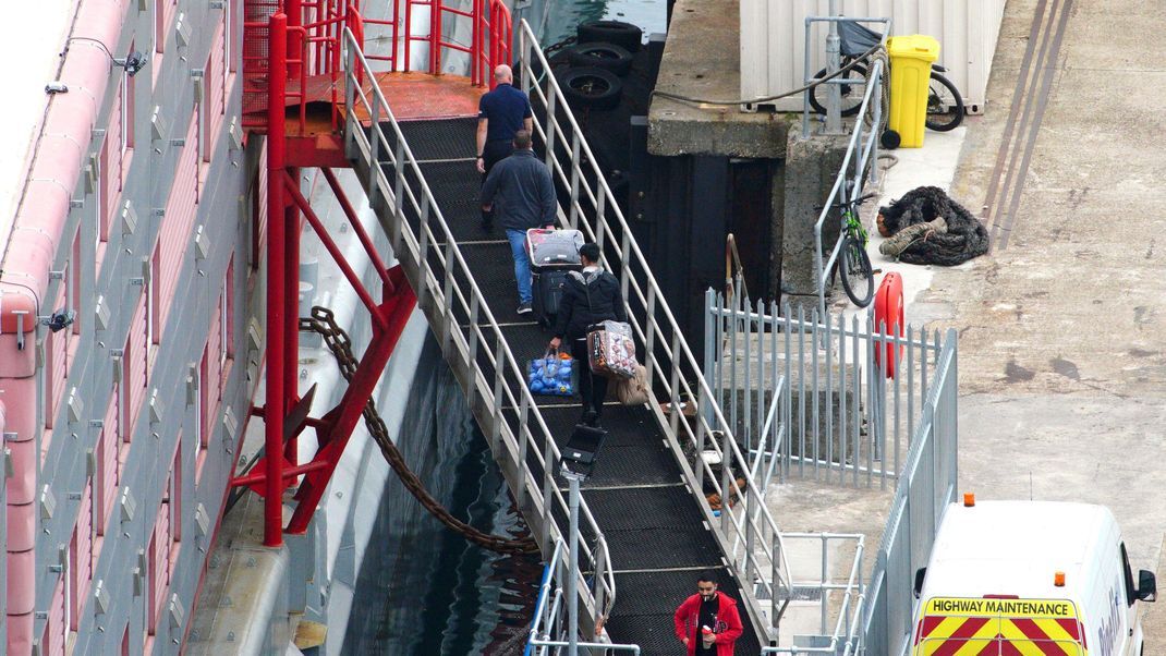 Menschen gehen im Hafen von Portland an Bord des Unterkunftsschiffs "Bibby Stockholm".