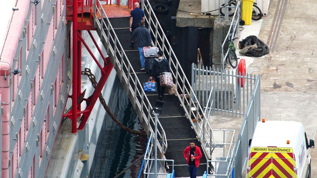 Menschen gehen im Hafen von Portland an Bord des Unterkunftsschiffs «Bibby Stockholm»