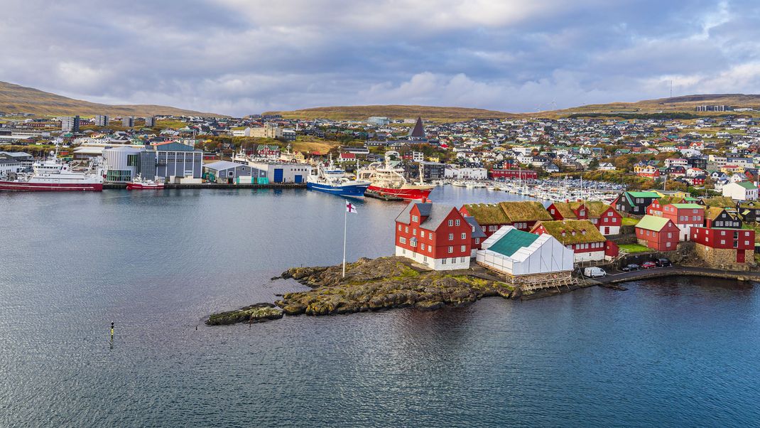 Färöer: Torshavn ist die Hauptstadt der Färöer-Inseln. Sie liegt auf der Hauptinsel Streymoys und hat gut 14.000 Einwohner:innen. Übersetzt heißt Färöer: „die Schafsinseln“. So zeigt das Wappen auch ein Schaf auf blauem Grund. Seit 2005 gelten die Färinger:innen als gleichberechtigte Nation innerhalb des dänischen Königreiches.