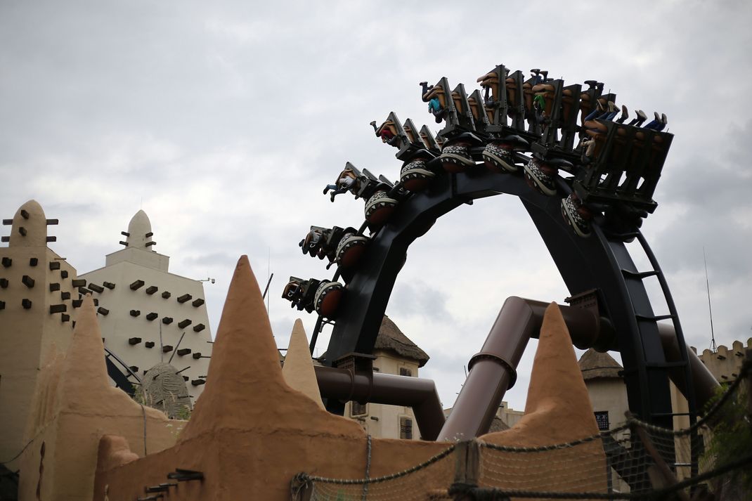 Besucher fahren in Brühl im Freizeitpark Phantasialand mit einer Achterbahn.