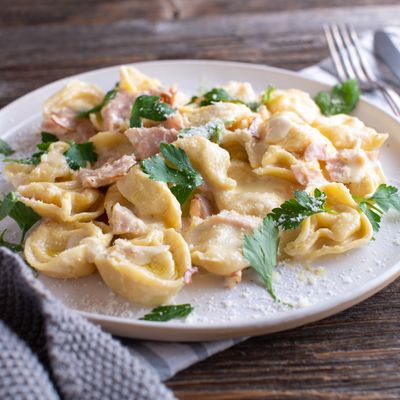 Plate with italian pasta dish. Tortellini with ham, parmesan cheese and parsley in a delicious cream sauce