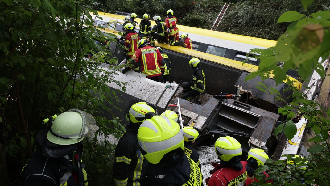 Rettungskräfte suchen in einem entgleisten Zug nach Fahrgästen. Foto: Thomas Warnack/dpa +++ dpa-Bildfunk +++