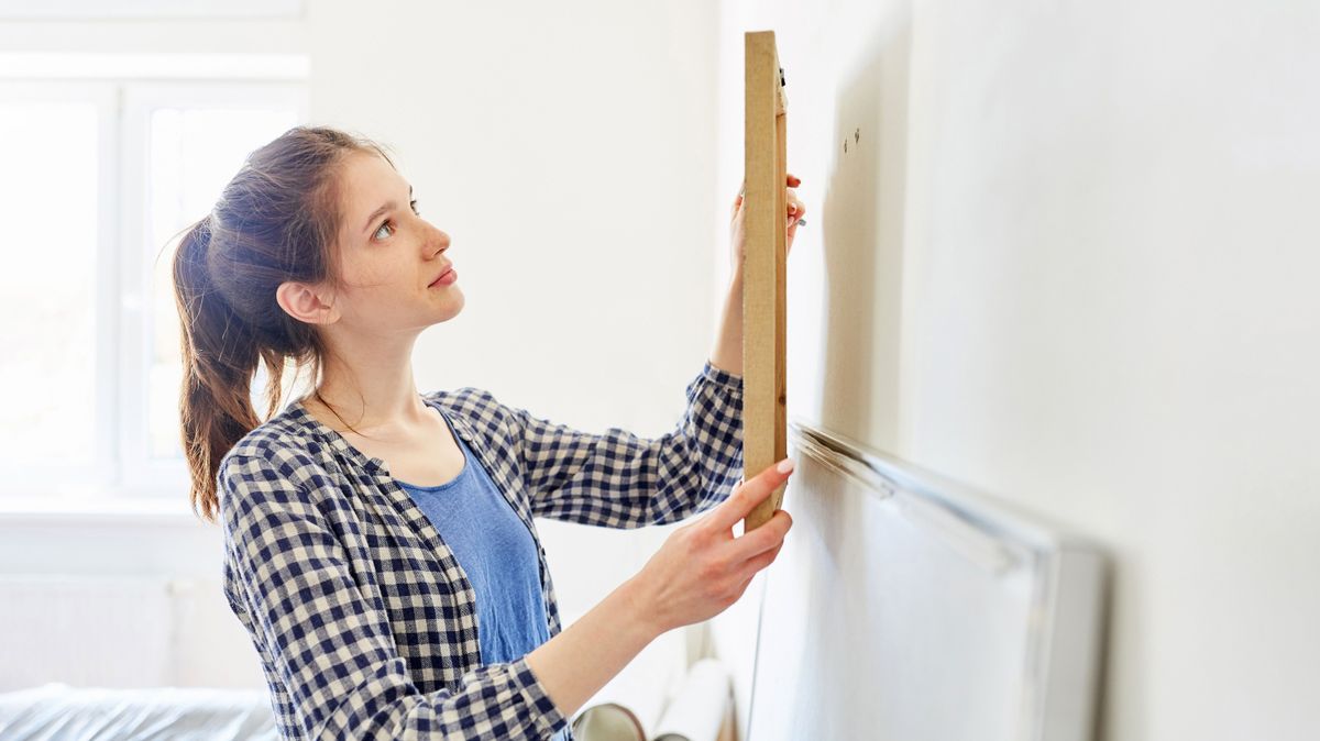 Junge Frau als Heimwerker beim Bild aufhängen