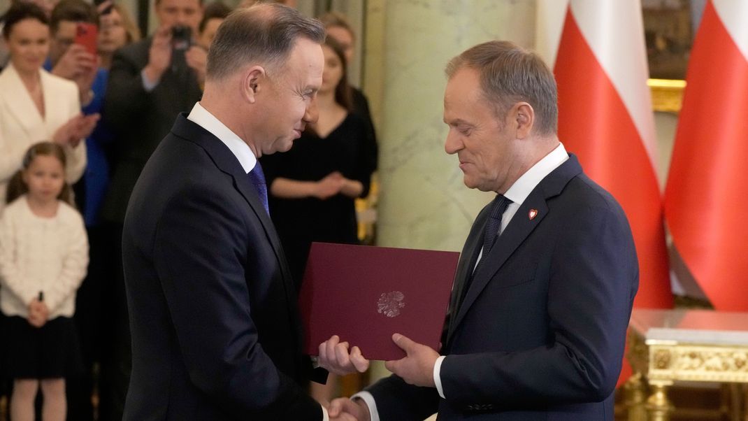 Andrzej Duda (links), Präsident von Polen, und Donald Tusk, neuer Ministerpräsident von Polen, geben sich die Hand während der Vereidigung der neuen Regierung im Präsidentenpalast.