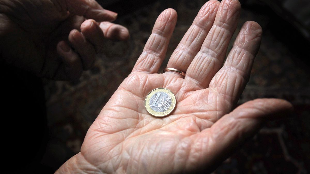 Eine 83-jährige Frau hält eine Euromünze in der Hand.