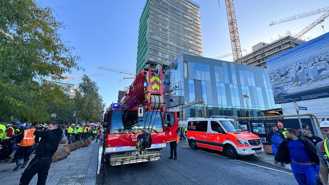 Einsatzfahrzeuge der Feuerwehr stehen vor einem eingerüsteten Hochhaus. Hier ereignete sich das Unglück.