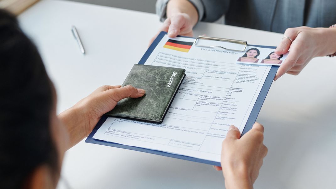 High angle view of unrecognizable woman applying for visa in embassy giving passport and application form to specialist