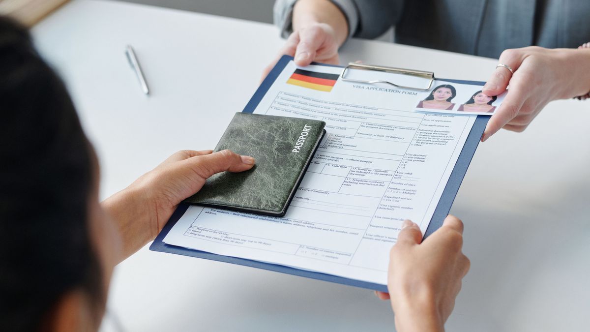 High angle view of unrecognizable woman applying for visa in embassy giving passport and application form to specialist
