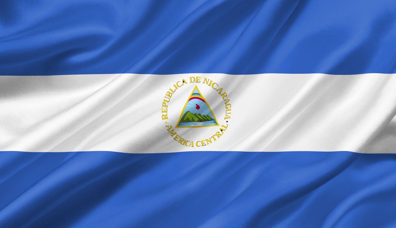 Nicaragua, gelegen in Mittelamerika, legte sich erst 1908 auf seine Flagge fest. Um darin das Lila zu finden, musst du genau hinschauen - es versteckt sich im Regenbogen in der Fahnenmitte.