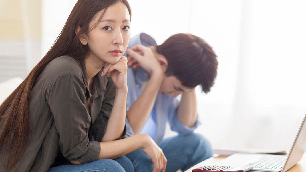 Upset couple using laptop at home.