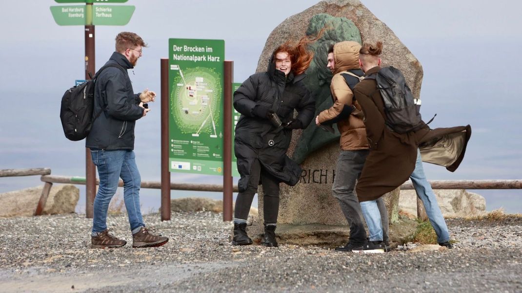 Besucher:innen auf dem Brocken halten sich am Heinrich-Heine-Gedenkstein fest. Aufgrund einer Unwetterwarnung wird vor Ausflügen auf den Brocken gewarnt.